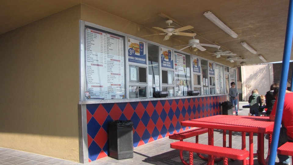 Outdoor tables beside a fast-food hamburger restaurant.